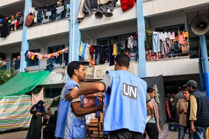 Workers of the United Nations Relief and Works Agency for Palestine Refugees (UNRWA) agency talk together in the playground of an UNRWA-run school that has been converted into a shelter for displaced Palestinians in Khan Yunis in the southern Gaza Strip on October 25, 2023, amid the ongoing battles between Israel and the Palestinian group Hamas. (Photo by Mahmud HAMS / AFP)
